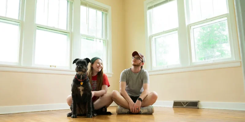 Home buyers and their dog in the empty living room of their next home discussing the Northeast Florida housing market
